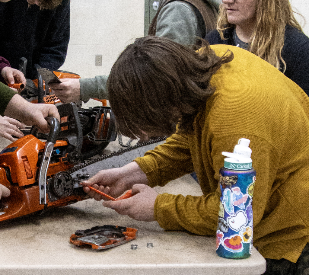 visiting student works on a chain saw