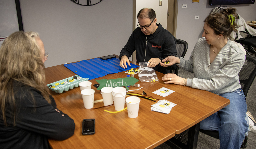 3 adults work on math activities in workshop