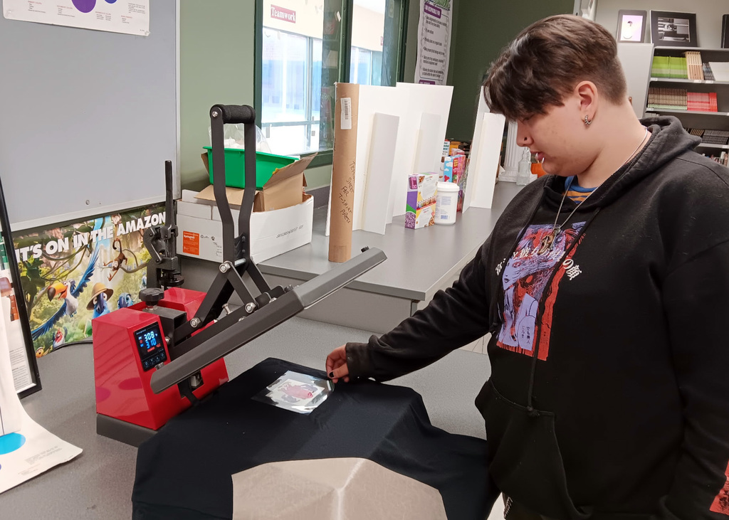 student works with t-shirt press