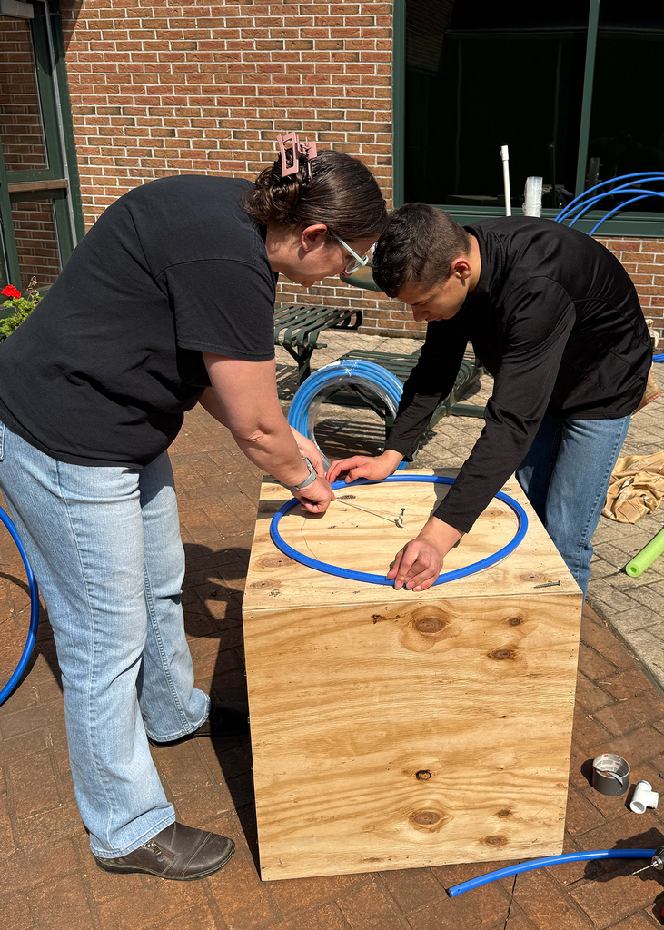 teacher helps student work with flexible pipe