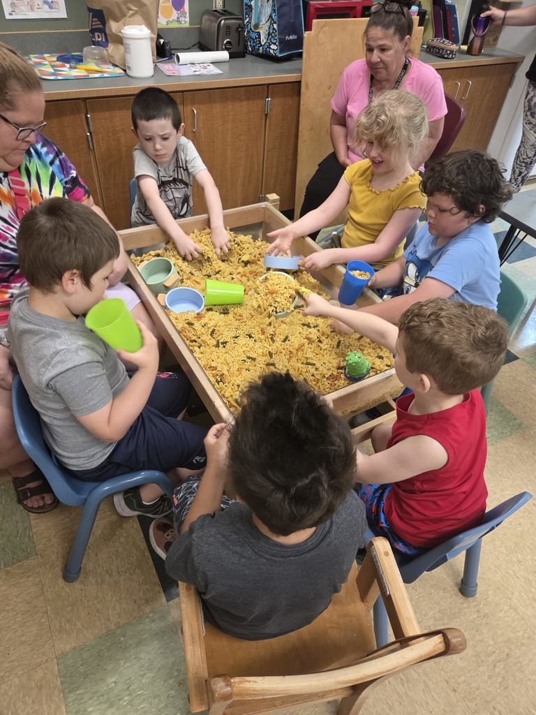 2 teachers and 5 students play in macaroni box