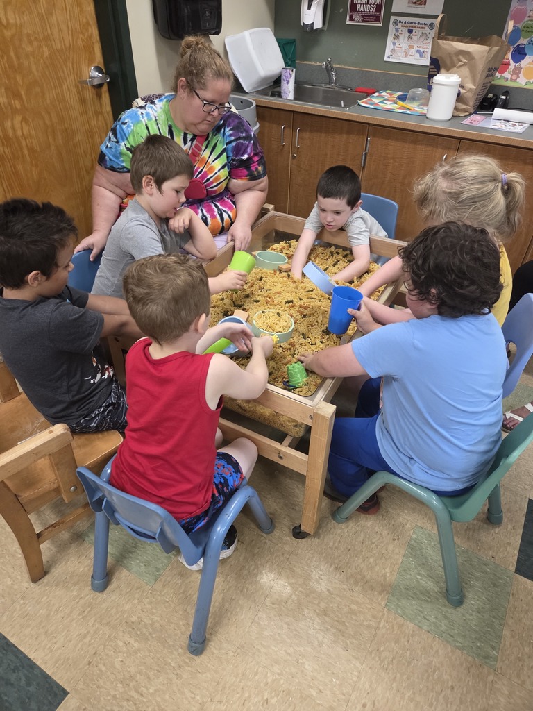 teacher watches students playing in macaroni box