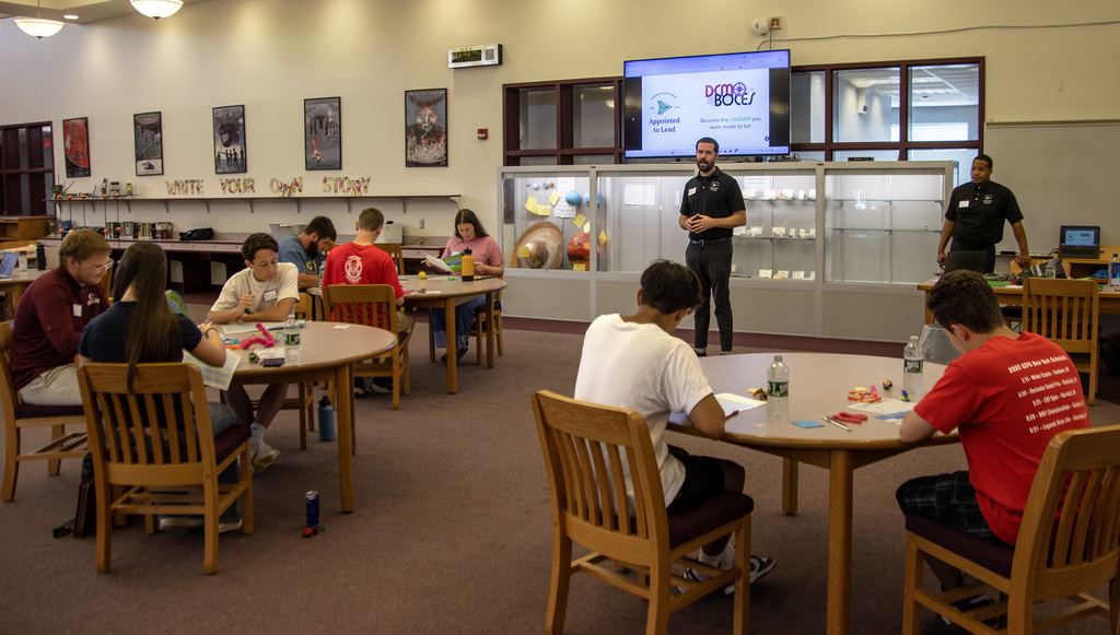 presenter talks to students who are working at tables