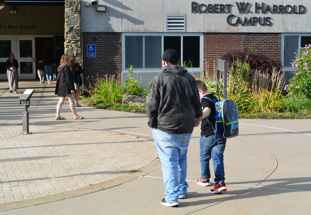 adult and student head for entrance of school building