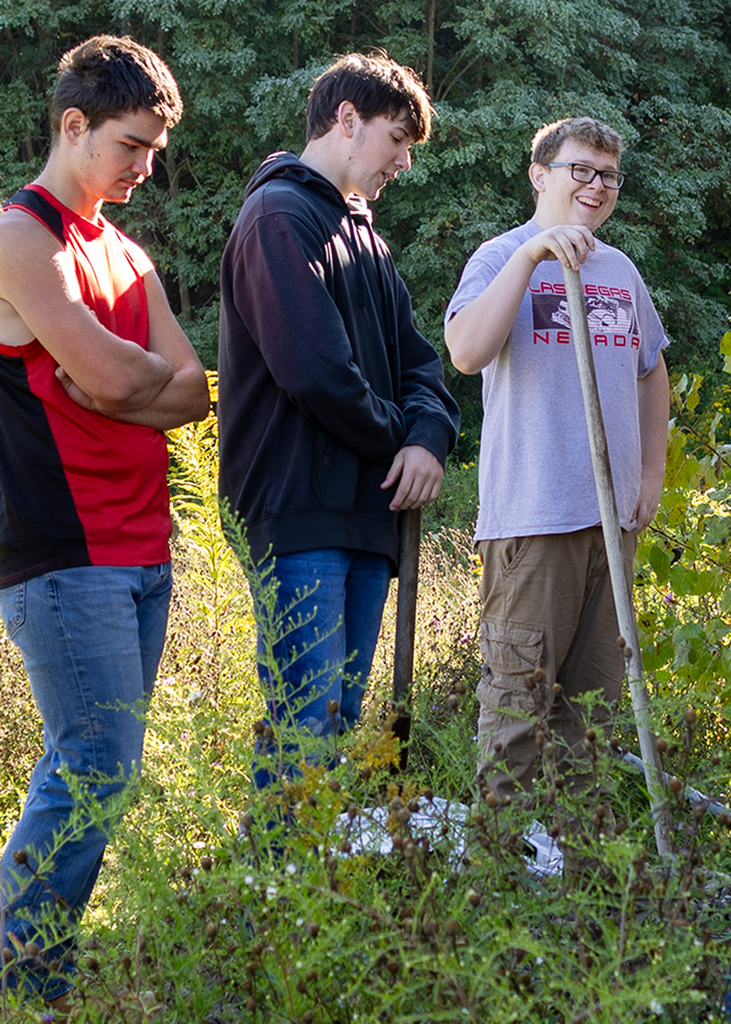 student smiling, 2 other students with him
