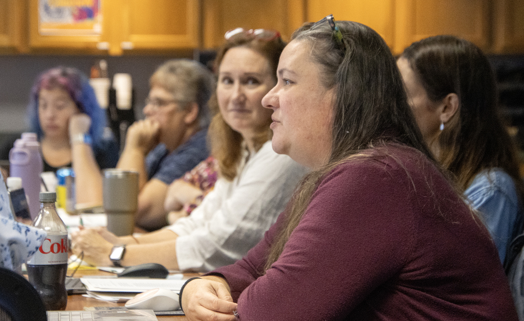 close up of woman speaking; others look and listen
