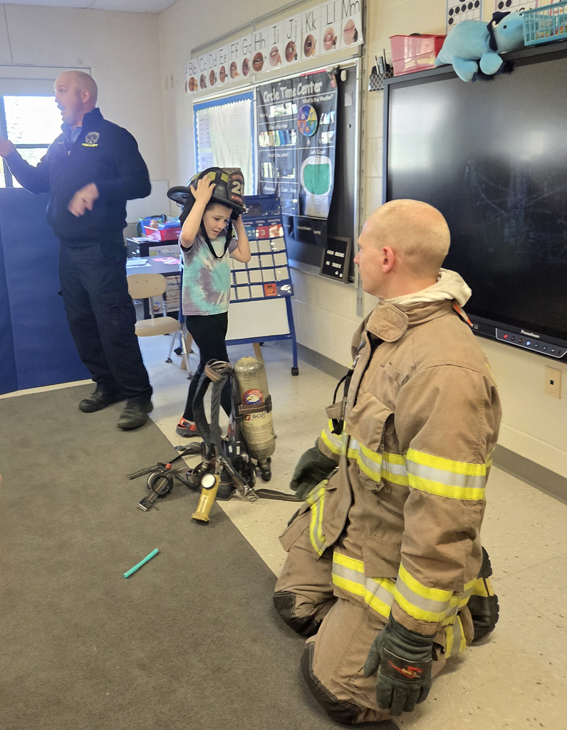 firefighter in turnout gear with students and another firefighter