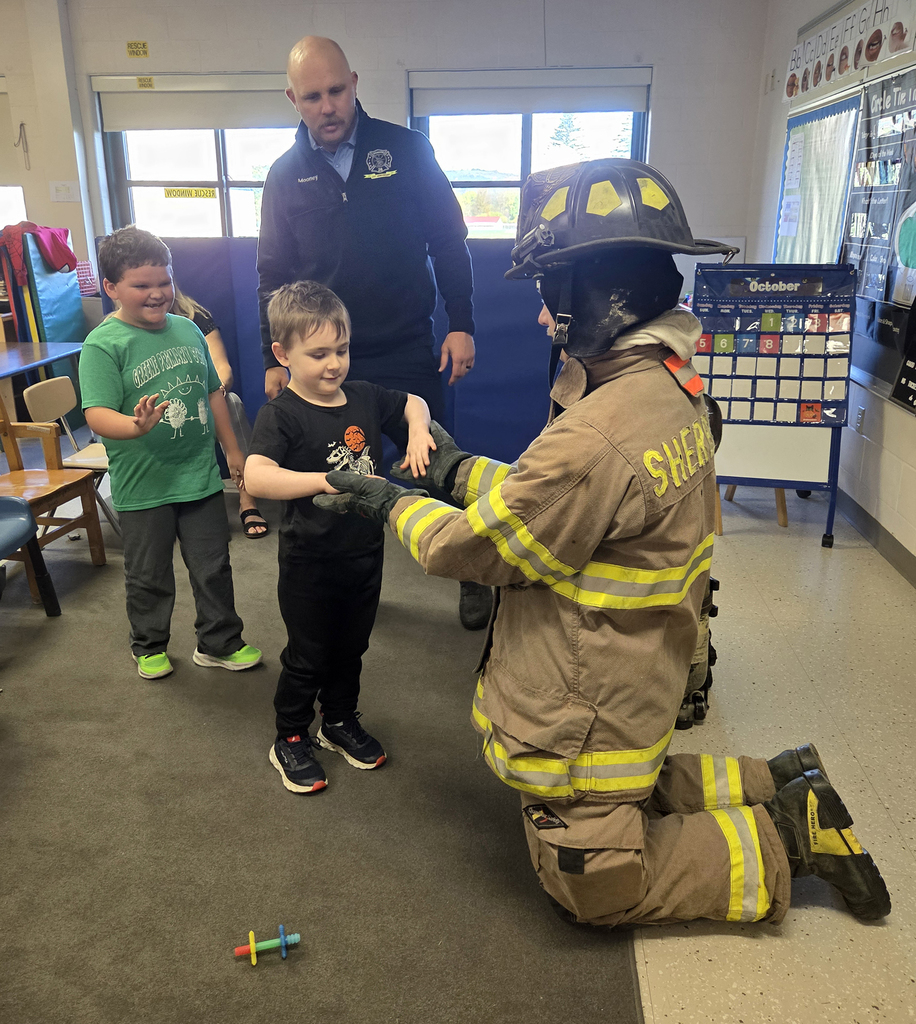 firefighter in turnout gear with students and another firefighter