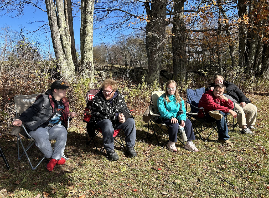 5 students sitting in folding chairs outside