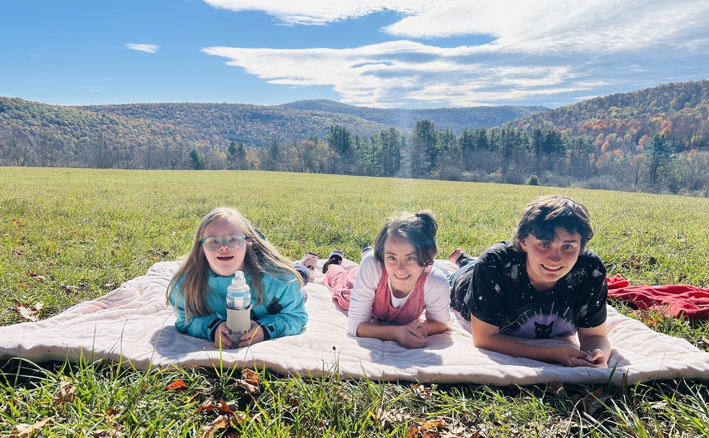 3 students lying on a blanket in a field