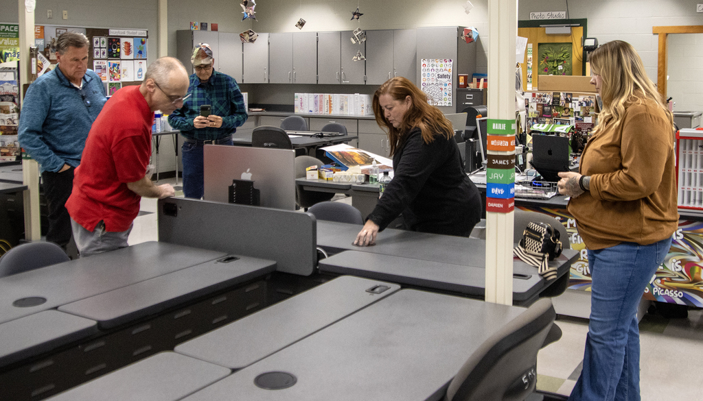 5 adults looking at Visual Communications equipment