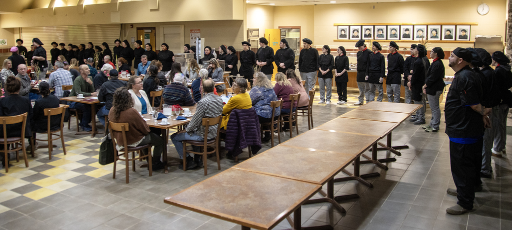 culinary students stand around diners as they're recognized
