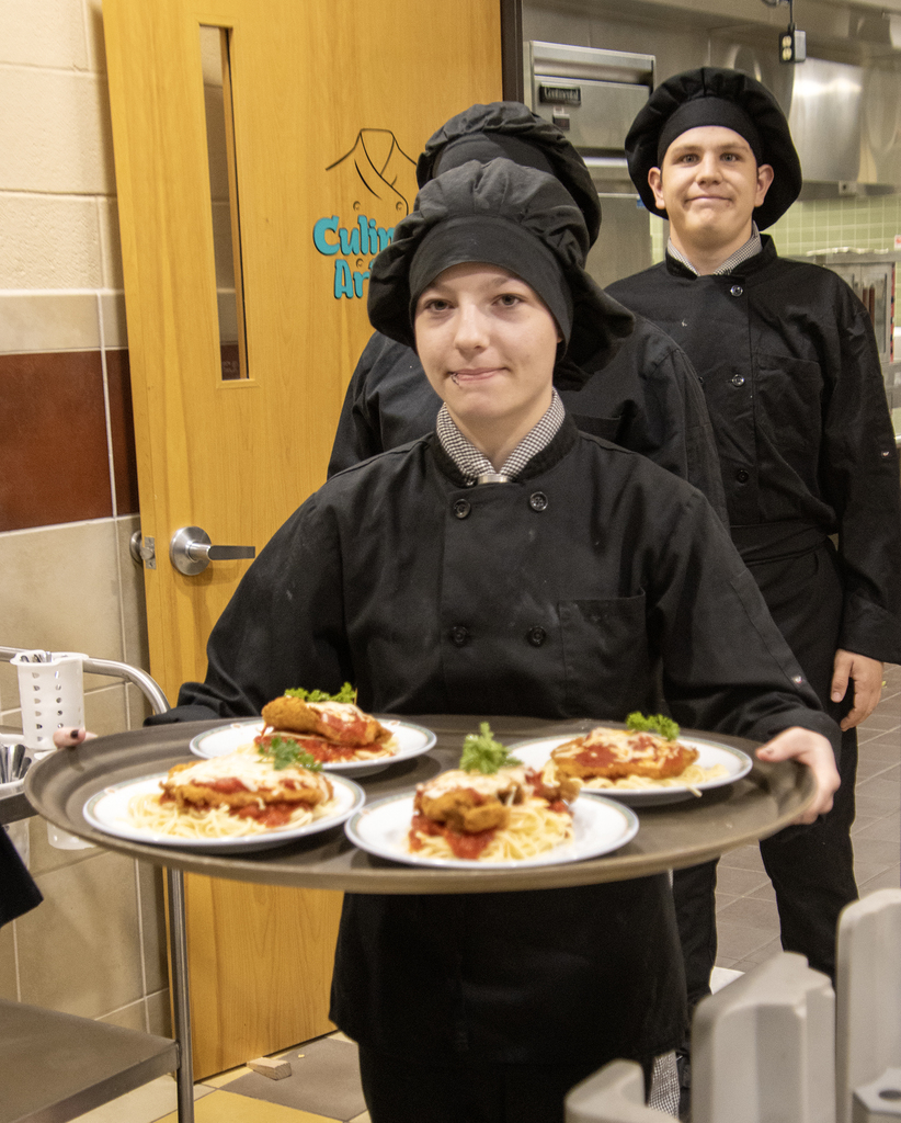 student holding tray of dinners