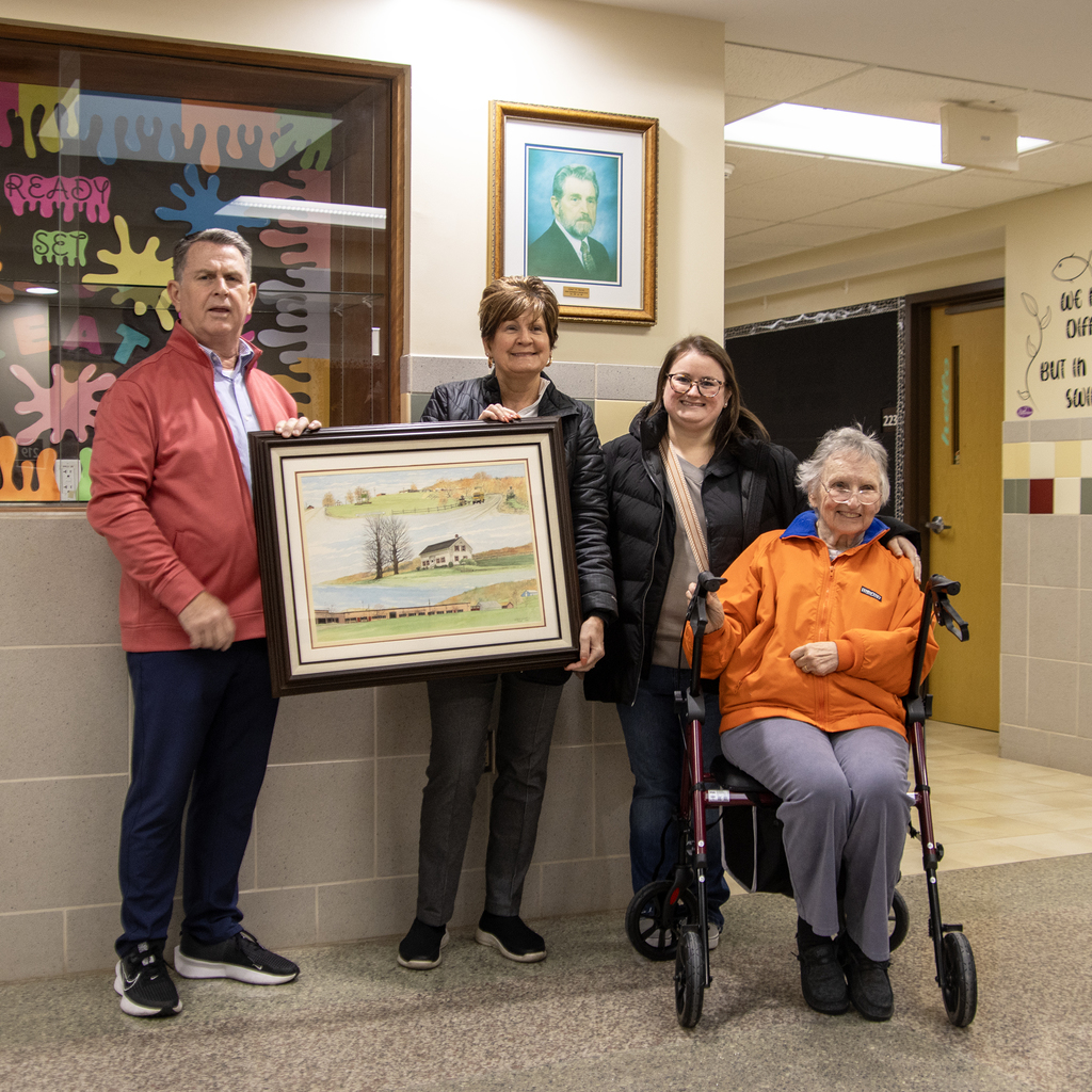 Scott Harrold, his wife, daughter and mother posein front of a picture of Robert W. Harrold with the painting they donated