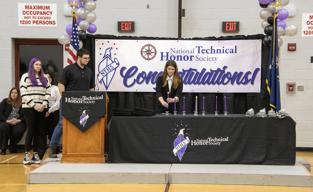 3 NTHS students on stage with candles