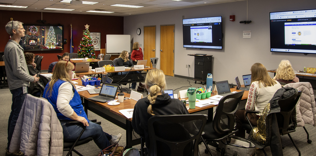 adults in a conference room looking at the screens