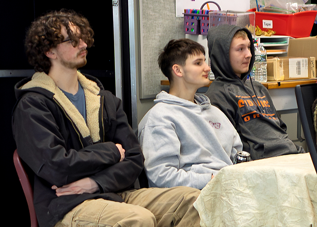 3 students listening to speaker