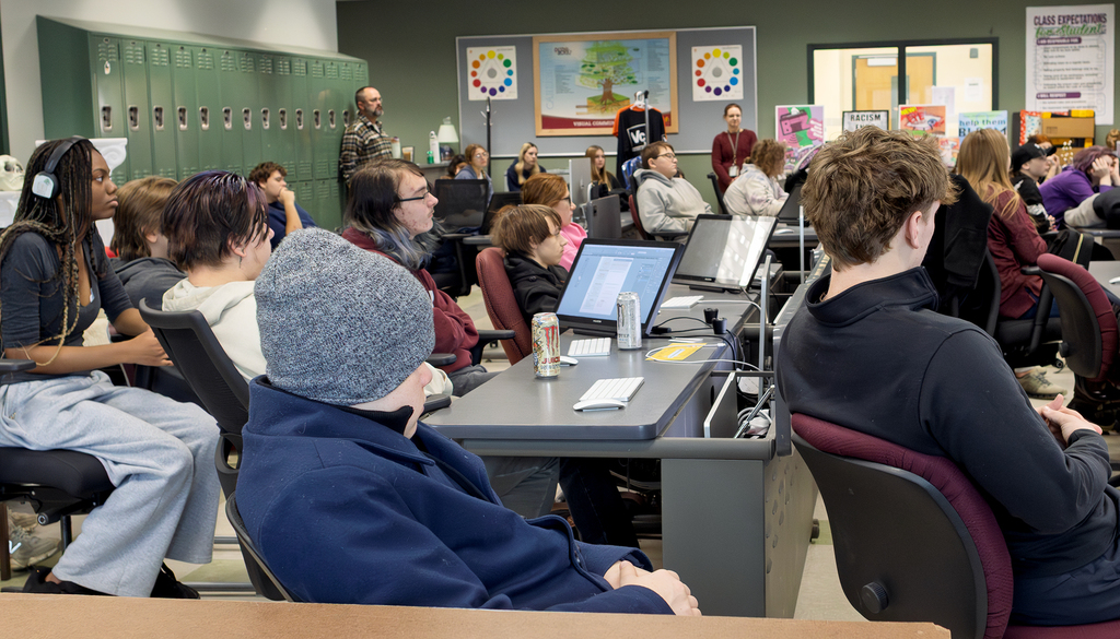 room full of students and teachers listening to speaker