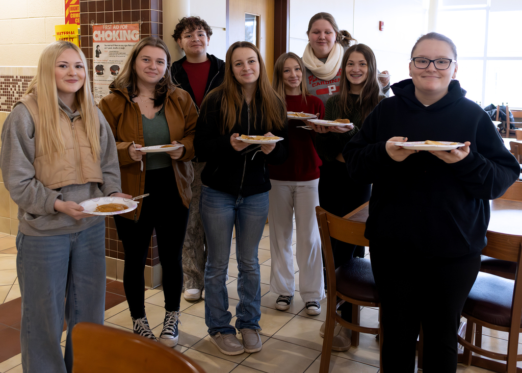 cosmetology students pose with plates of pancakes