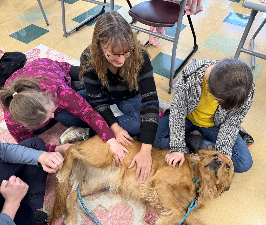 2 students and an aide petting the dog