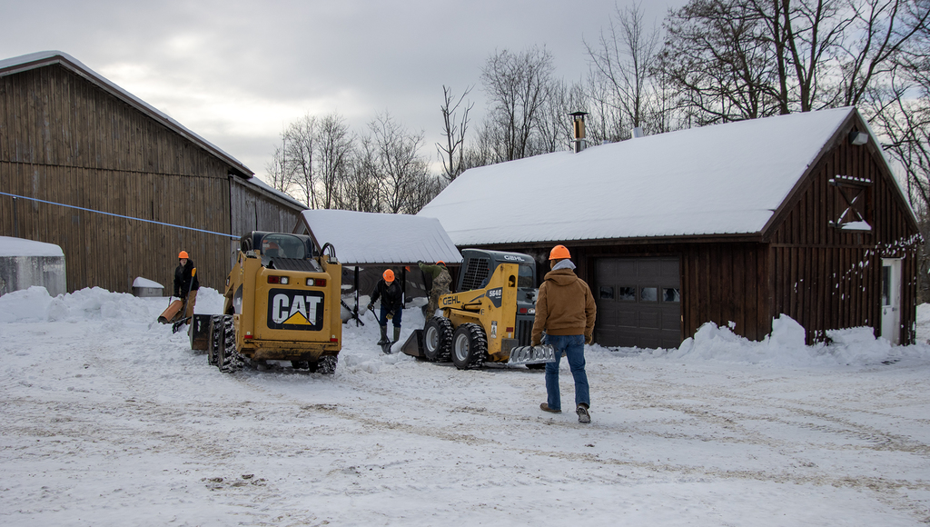 conservation students moving snow outside maple building