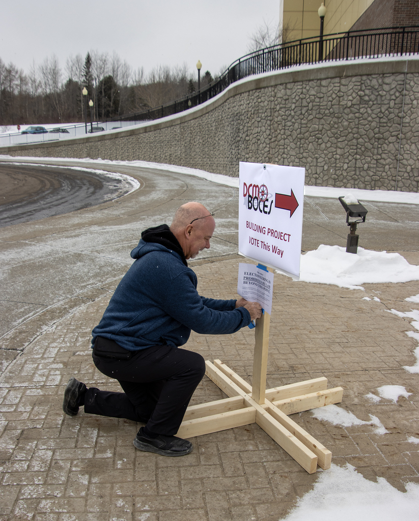 Rick Shaw affixes polling place sign to post