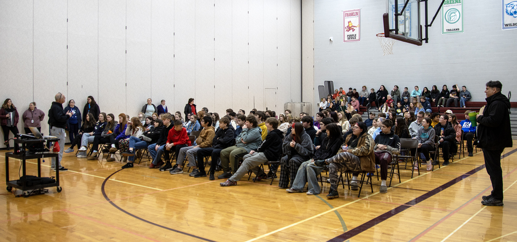Assistant Principal speaks to students assembled in gym
