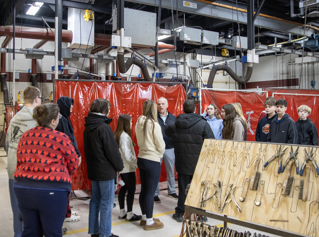 assistant principal speaks to group of students in welding lab