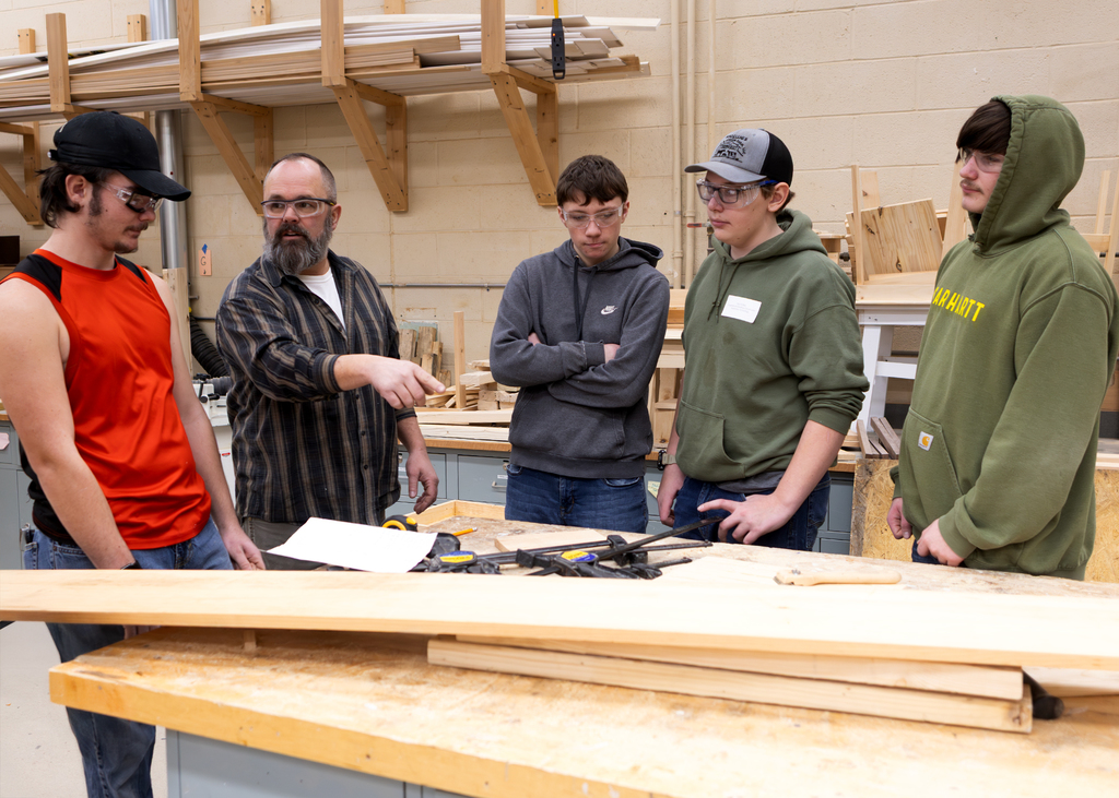 Carpentry teacher speaking with 3 visiting students
