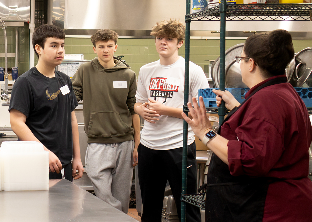 Culinary teacher speaking to 3 visiting students