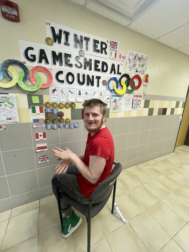 student smiling at Winter Olympics Medal count wall