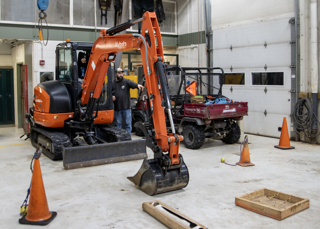 Mr. Larsen guides a student in an excavator