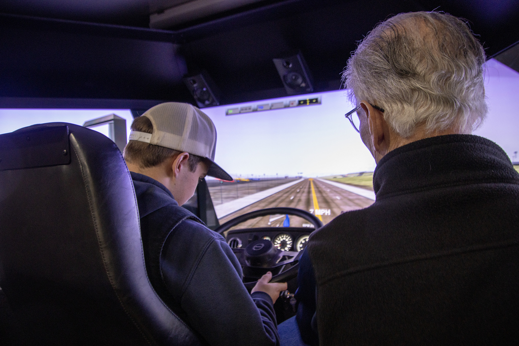 instructor and student in truck driving simulator; student is at the wheel 