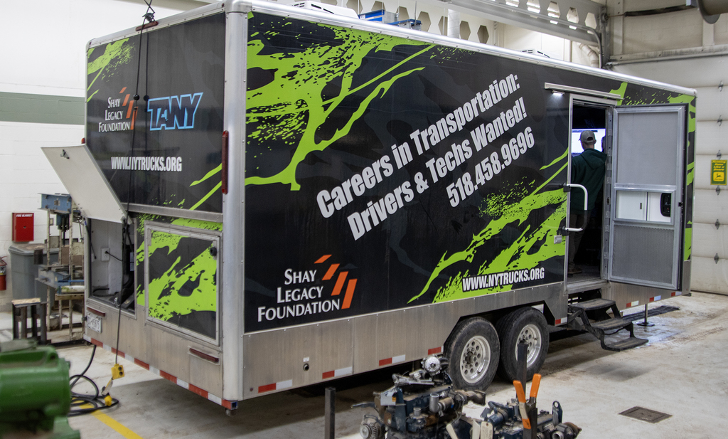 large truck-towed trailer; "Careers in Transportation: Drivers & Techs Wanted!" written on the side