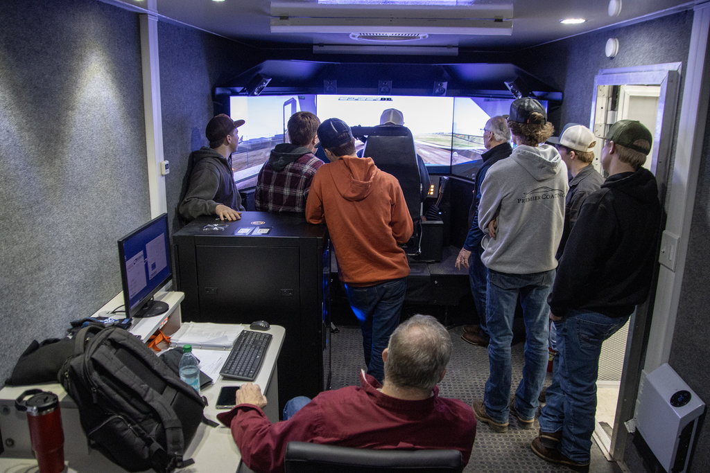 2 instructors and 5 students inside truck driving simulator 