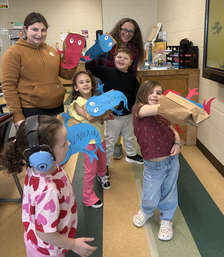 2 teachers and students show off fish puppets they made