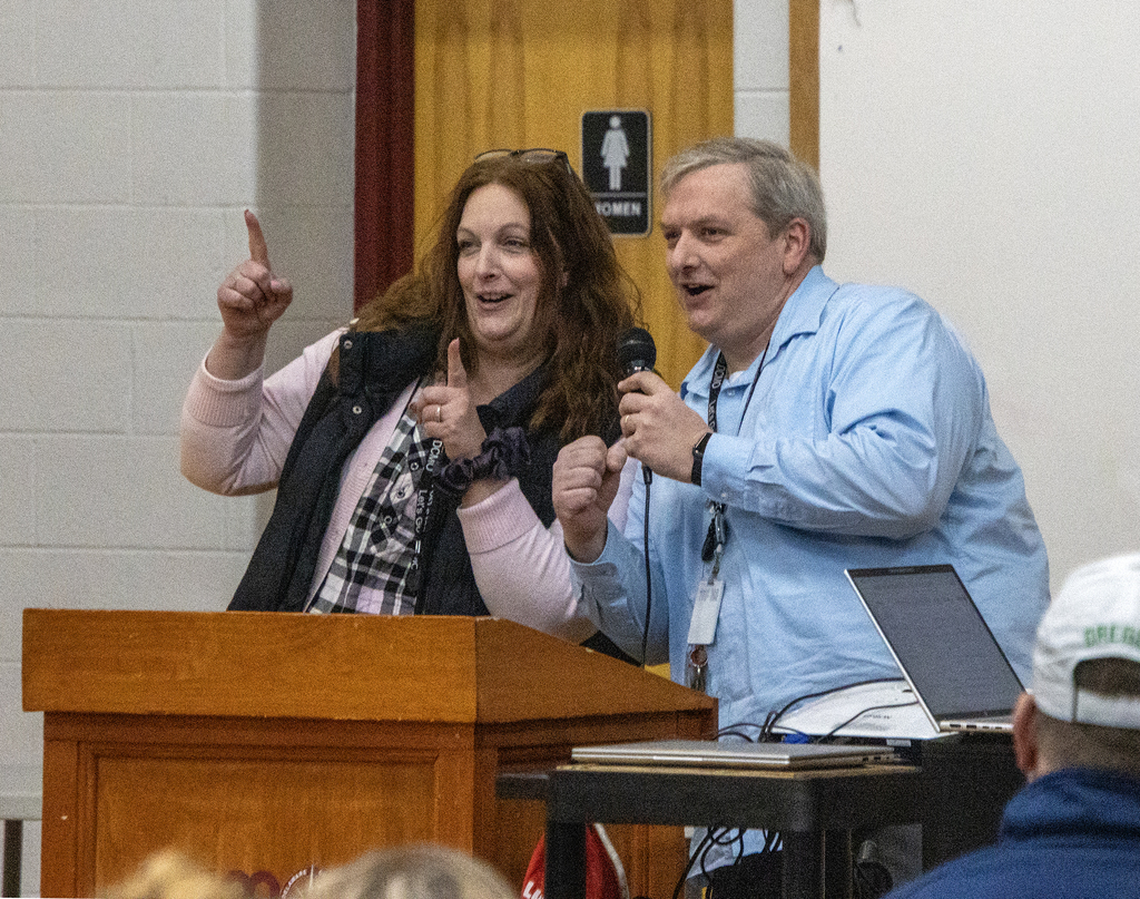 Roula and Ryan, campus principals, smiling and gesturing at the lectern