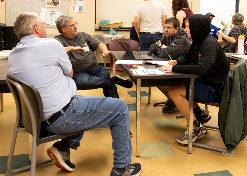 2 carpenters union representatives speak with two students