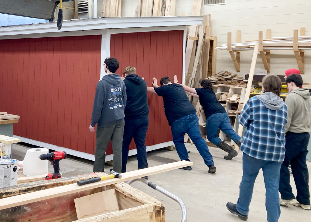 students pushing a building out the door