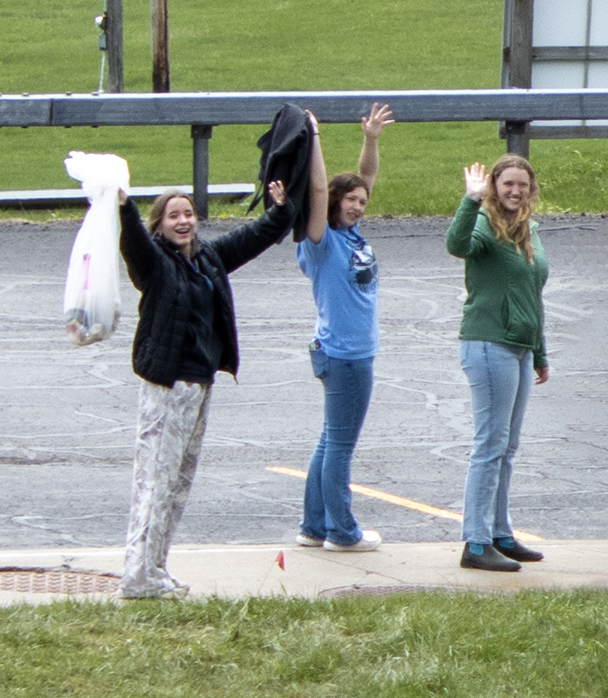3 students pose with a trash bag after picking up litter