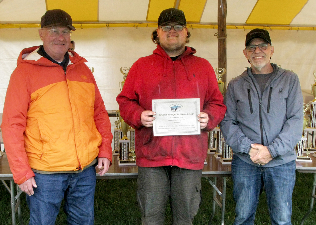 Jakob Depew holds a certificate, flanked by his instructor and a representative of the Norwich Car Club