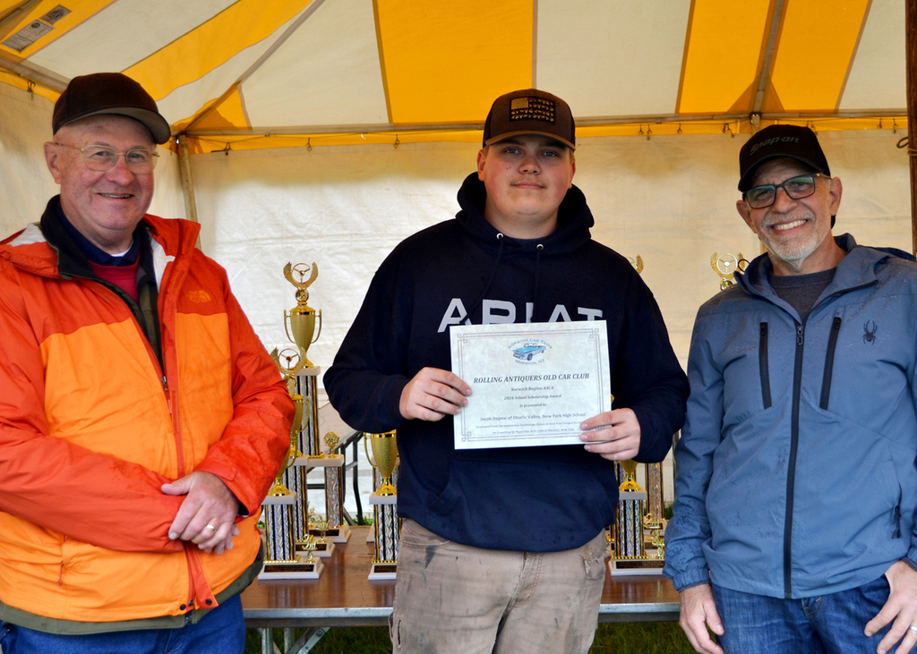 Jackson Barker holds a certificate, flanked by his instructor and a representative of the Norwich Car Club