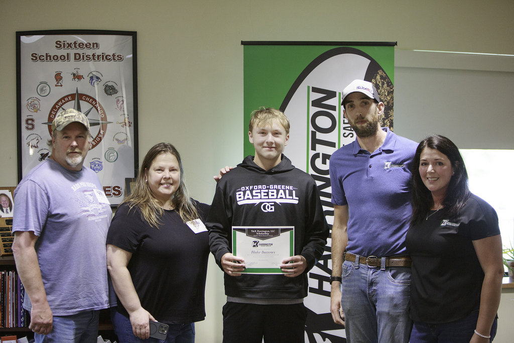 Blake Barrows receives a certificate from two representatives of T & K Harrington;his parents are also standing with him
