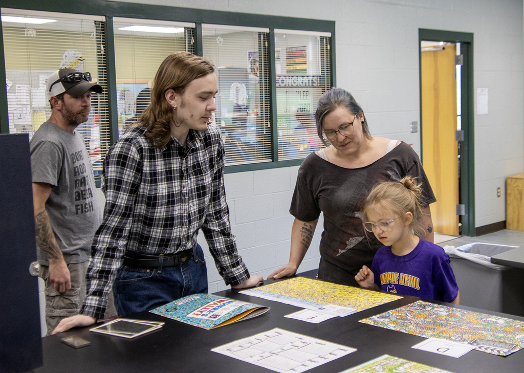 Student showing the Where's Waldo game to family members