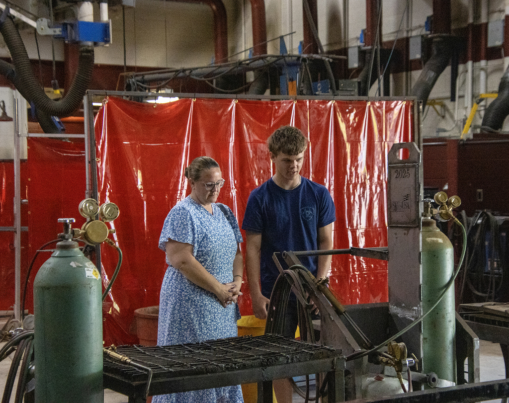 student shows his mother welding equipment and projects