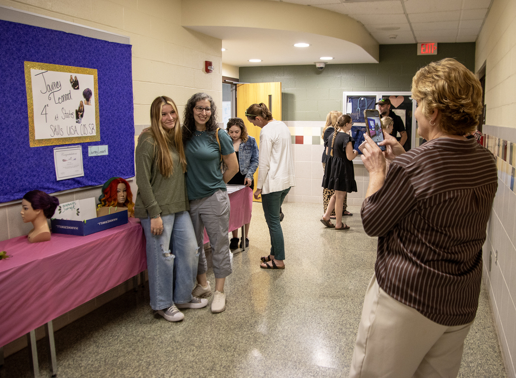 student and mother pose for photo being taken by instructor