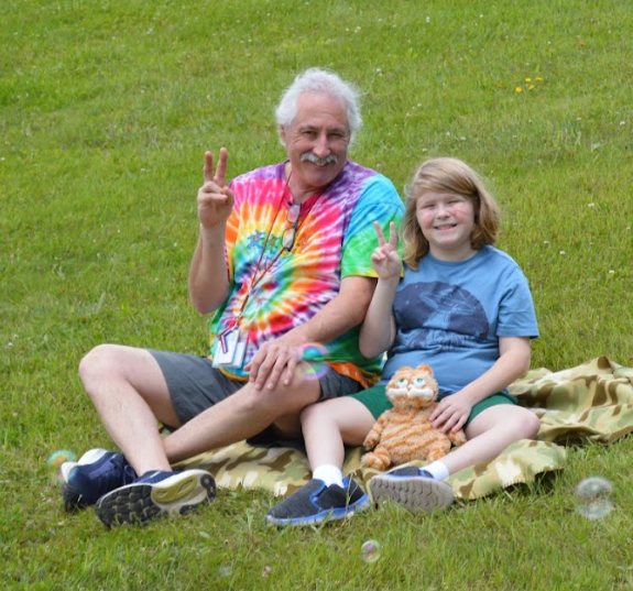 teacher and student both giving the peace sign, sitting on the lawn