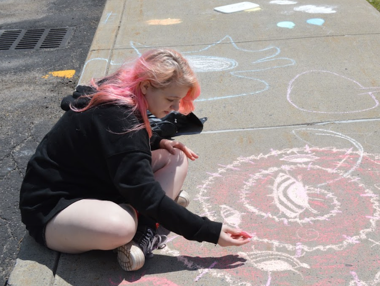 student doing chalk art on sidewalk