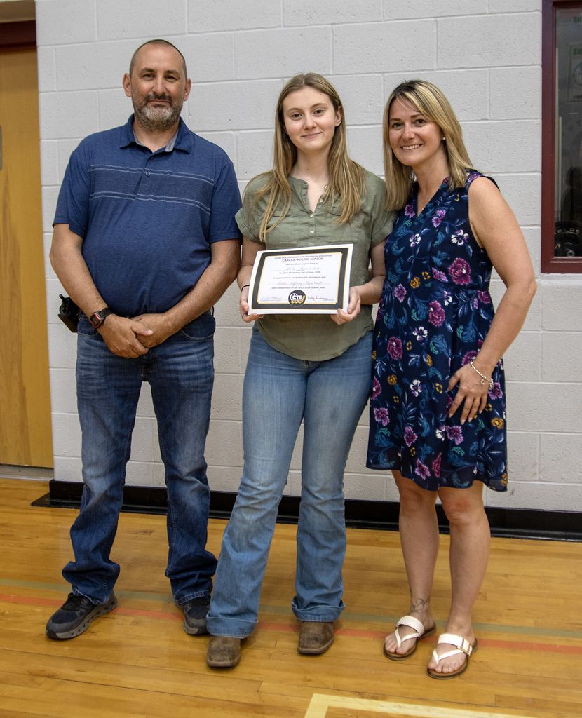 student poses with their dad and high school principal