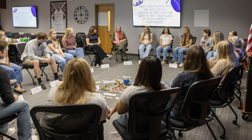 20 students and adults sitting in a circle having a conversation